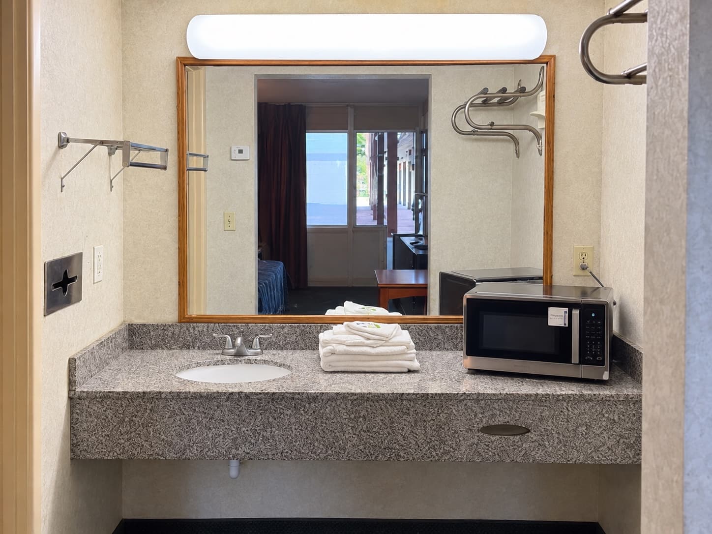 Guest bathroom vanity with sink, mirror, towels, and microwave